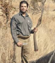 Don Trump Jr holding the tail of an elephant he just killed for Sport